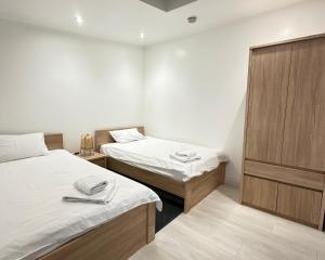 a bedroom with two beds and a wooden cabinet at Annex at Orchard House - Strictly No Parties in Barton in the Clay