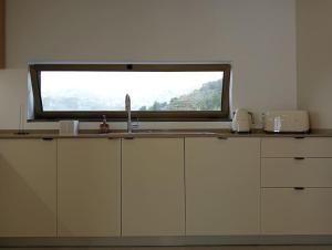 a kitchen with a counter with a sink and a window at Villa Amendoa in Arco da Calheta