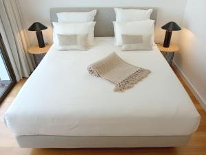 a large white bed with white pillows and two lamps at Villa Amendoa in Arco da Calheta