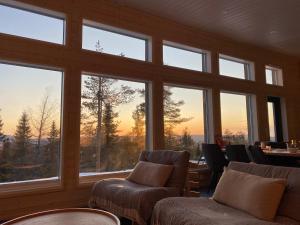 Zimmer mit großen Fenstern, Stühlen und einem Tisch in der Unterkunft Näköalahuvila Pikku-Syötteen Helmi in Syöte