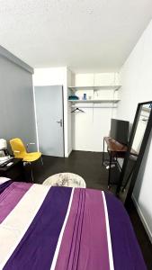 een slaapkamer met een paars en wit bed en een bureau bij Olympique 700m du Stade de France in Saint-Denis