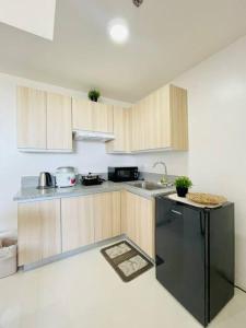 a kitchen with wooden cabinets and a black refrigerator at WV 6 Simple and Cozy in Iloilo City