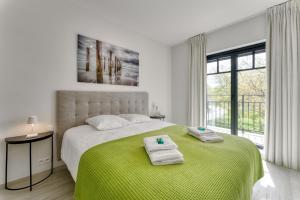 Un dormitorio blanco con una cama grande con toallas. en Zonnig Luxueuze Appartementen La Coronne, en Knokke-Heist