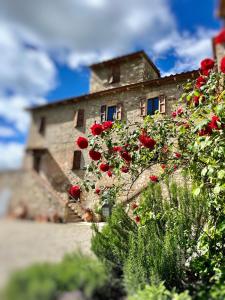 a stone building with red roses in front of it at Casale Collecchio Siena in Siena