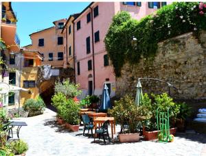 un patio al aire libre con mesas, sillas y plantas en La Casa nel Borgo, en Ameglia