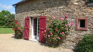 een stenen gebouw met rode luiken en roze bloemen bij Brimbilly, maison de charme in Guenrouet