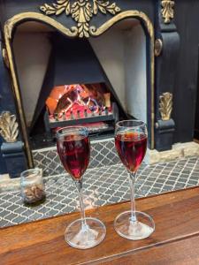 two glasses of red wine on a table with a fireplace at Ing at Sandstone in Fouriesburg