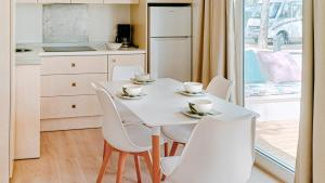 a kitchen with a white table and white chairs at Camping Relax Sol in Torredembarra