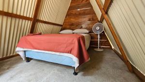um pequeno quarto no sótão com uma cama e uma ventoinha em Glamping El Pájarero em San Juan La Laguna