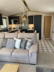 The Luxe Lodge, Skipsea Sands Bridlington في Ulrome: غرفة معيشة مع أريكة ومطبخ
