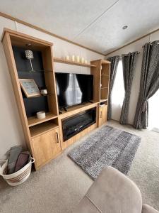 a living room with a tv and a entertainment center at The Luxe Lodge, Skipsea Sands Bridlington in Ulrome