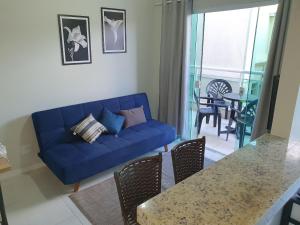 uma sala de estar com um sofá azul e uma mesa em AP encantador na Praia do Forte! (208) em Cabo Frio