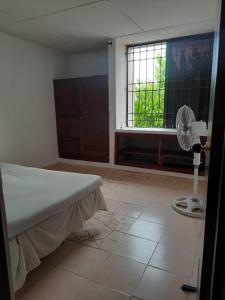 een slaapkamer met een bed en een raam met een ventilator bij Hostal las flores de Valledupar in Valledupar