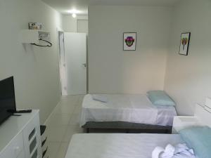 a white room with two beds and a mirror at AP encantador na Praia do Forte! (208) in Cabo Frio