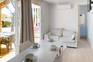 Camping Relax Sol في توريديمبارا: غرفة معيشة بيضاء مع طاولة وكراسي بيضاء