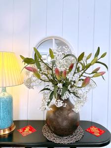 a vase of flowers on a table next to a lamp at Moon Homestay in Thôn Kim Long (1)