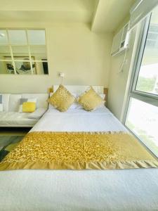 una camera da letto con un grande letto bianco con lenzuola dorate di N2 Sleek Urban Escape a Città di Iloilo