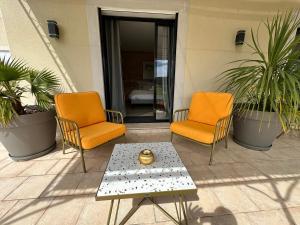 - 2 chaises orange et une table basse sur la terrasse dans l'établissement Bastide Saint-Thomé, à Saint-Thomé