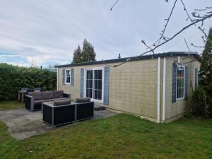 a tiny house with two couches in a yard at Camping Goedereede Chalet nr 16 in Goedereede