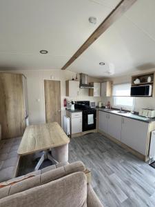 a kitchen and living room with a wooden table at Cosy Caravan in Ulrome