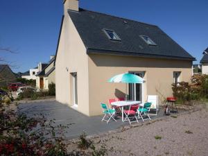 una mesa y sillas con sombrilla frente a una casa en PLEHEREL PLAGE Location saisonnière 4-5 personnes, en Fréhel