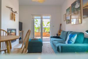 uma sala de estar com um sofá azul e uma mesa em Surf GuestHouse - 7min walk to the beach em Pataias