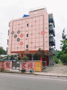 un bâtiment rose avec des écritures sur son côté dans l'établissement Changlong Inn, à Wufeng
