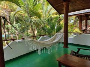 a hammock on the porch of a resort with palm trees at Panorama Beach Hotel in Tangalle