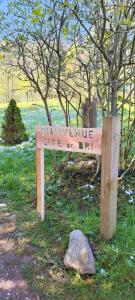 a wooden sign sitting in the grass next to a tree at LE GITE DE BRI in Orbey