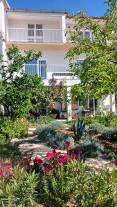 a garden in front of a building with flowers at Neptun in Primošten