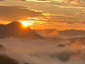 a misty sunrise in the mountains with the sun setting at Zhangjiajie Tingyutang Little Yard in Zhangjiajie