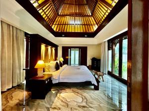 a bedroom with a large bed with a large ceiling at Mai Villa in Jimbaran