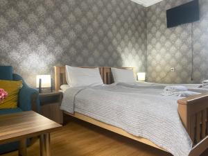 1 dormitorio con 1 cama grande y 1 silla azul en Hillside Guesthouse, en Borjomi