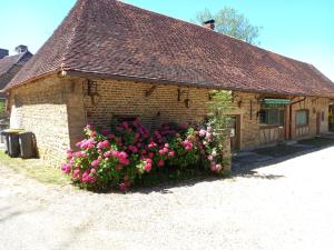 ein Backsteingebäude mit rosa Blumen davor in der Unterkunft Moulin de Sauvagette in Saillenard
