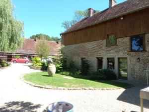 a brick house with a yard with a car in the background at Moulin de Sauvagette in Saillenard