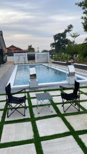 a swimming pool with two chairs and a table at Anjung Barakah Chalet in Kuala Terengganu