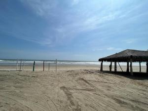 een zandstrand met een strohut en de oceaan bij Arenal's Beach Home in Playas