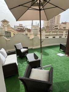 een patio met stoelen en een parasol op een dak bij Estudio triple con terraza y vistas en el centro in Albacete