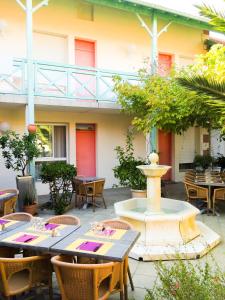 a patio with a fountain and tables and chairs at Hôtel Orange Marine in Arcachon