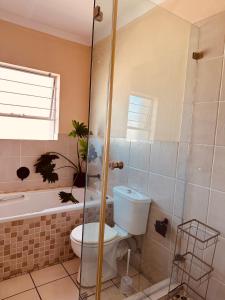 a bathroom with a toilet and a shower and a tub at Shepherds Inn in Boksburg