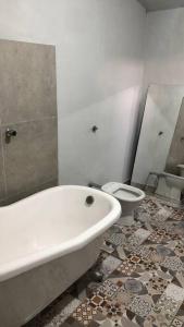 La salle de bains est pourvue d'une baignoire blanche et de toilettes. dans l'établissement Hospedagem em meio a natureza!, à Águas da Prata