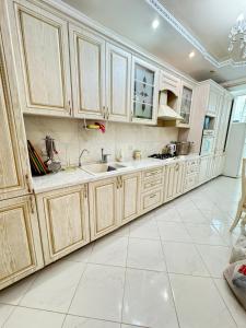 een keuken met houten kasten en een witte tegelvloer bij Люкс апартаменты в Актобе in Aqtöbe