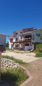 a large white house with a patio in front of it at Apartmani Rab - Adrijana & Aleksandra in Banjol