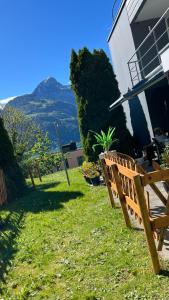 a wooden bench sitting in the grass next to a house at Wohnung „Perla Paradiso“ in Fluelen