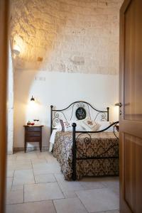 a bedroom with a bed and a stone wall at Trulli Magravì - Apparthotel in Alberobello