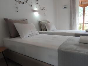 2 camas blancas en una habitación con ventana en The Port, en Porto Koufo