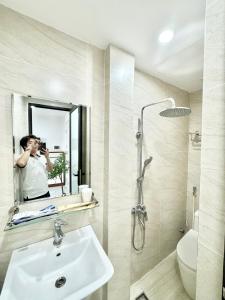 a man taking a picture in a bathroom mirror at The Little Home - Cù Chính Lan - Modern & Comfy Apartment in Hanoi