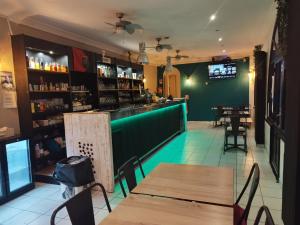 a restaurant with wooden tables and a green bar at Hôtel de la Loube in La Roquebrussanne