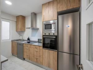 una cocina con nevera de acero inoxidable y armarios de madera en Central Alicante Urban Escape en Alicante