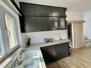 a kitchen with black cabinets and a sink at Elegant penthouse in Limassol in Limassol
